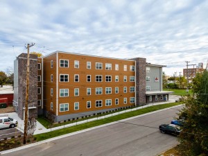 A modern multi-story apartment building with a combination of brown and gray exterior panels.