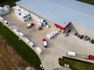 Aerial view of a warehouse with delivery trucks and storage containers in the yard.