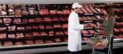 A customer interacting with a butcher in a grocery store meat section filled with various meat products.