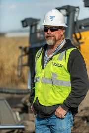 Man wearing a hard hat and safety vest standing on a construction site.