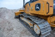 Bulldozer with tracks on a sandy surface at a construction site.