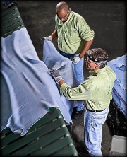 Two workers inspecting and handling large pieces of leather in a processing facility.
