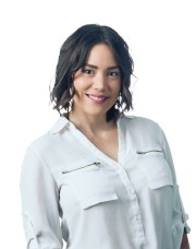 Woman with shoulder-length dark hair wearing a white shirt with zippers, smiling at the camera.