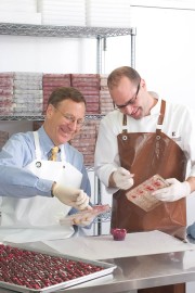Two chefs in a kitchen working on dessert preparation with molds and ingredients.