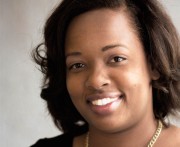 Close-up portrait of a woman with dark hair and a friendly smile against a neutral background.