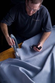A worker inspecting a piece of leather using measuring tools in a workshop setting.