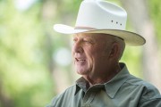Rancher with a white cowboy hat speaking outdoors, wearing a green shirt.