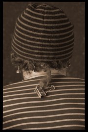 Individual wearing a striped beanie with a hair clip attached to their hair at the back.