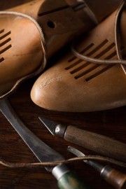 Wooden shoe forms with leather laces and tools including a knife and a wooden handle tool.