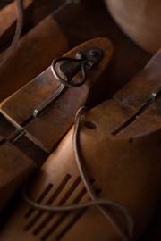 Collection of wooden shoe forms with metal and leather detailing arranged closely together.