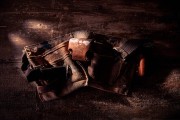 Brown tool belt with multiple pockets and metal clips resting on a wooden surface.